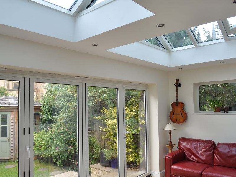 White Bi Fold doors with additional light being added by a duo of roof lanterns: Swipe To View More Images